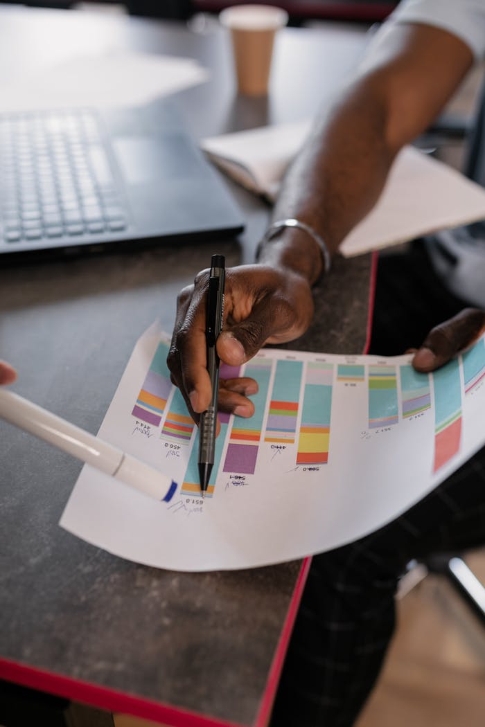 Close-up of hands analyzing colorful graphs at a business meeting, indicating strategic planning.
